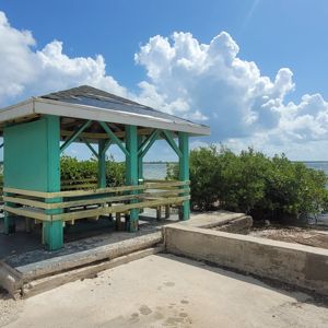 A waterfront gazebo with a clear view of the water and clouds.