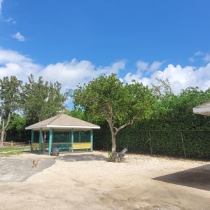 A park area with two gazebos, surrounded by greenery and a clear blue sky.