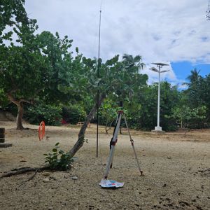 A radio setup under trees with an antenna and equipment on a tripod in a natural setting.