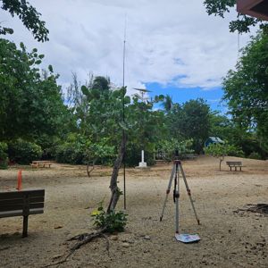 A portable radio station setup under trees with benches in a natural environment.