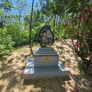 A monument with a sculpture surrounded by greenery and flowers.