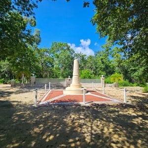 A commemorative monument surrounded by trees and a clear blue sky.