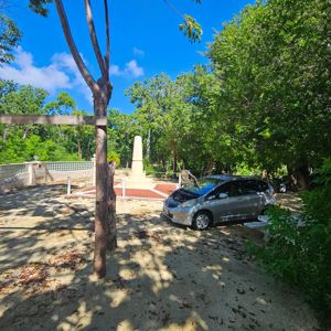 A clear view of a monument surrounded by trees, with a vehicle parked nearby.