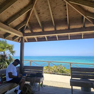 Operator seated at a wooden gazebo overlooking the ocean.