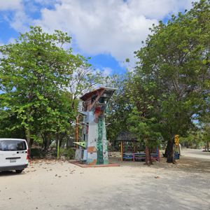 A radio activation setup near a colorful tower, surrounded by green trees and sandy ground.
