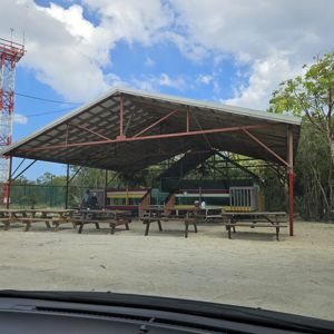 A covered shelter with picnic tables and a radio tower in the background.