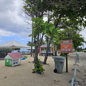 A view of Spot Bay Park with a sign, picnic tables, trees, and a tent.