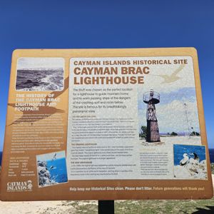 Photo of the Cayman Brac Lighthouse historical site sign with ocean background.