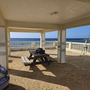 A shaded area near the ocean with a picnic table and radio equipment set up.