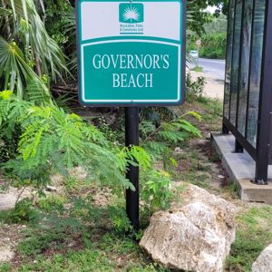 Sign indicating the entrance to Governor's Beach with lush greenery around.