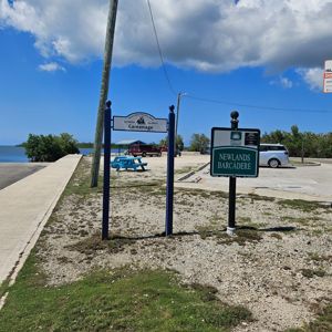 A sign indicating the location of the Careenage and Newlands Barcadere, with a scenic view of the water in the background.