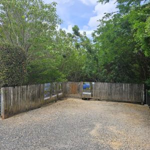 A fenced area surrounded by trees, with informational signs along the wooden fence.