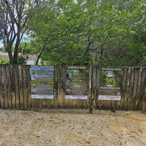 A wooden fence displaying three informational signs about local wildlife and conservation.